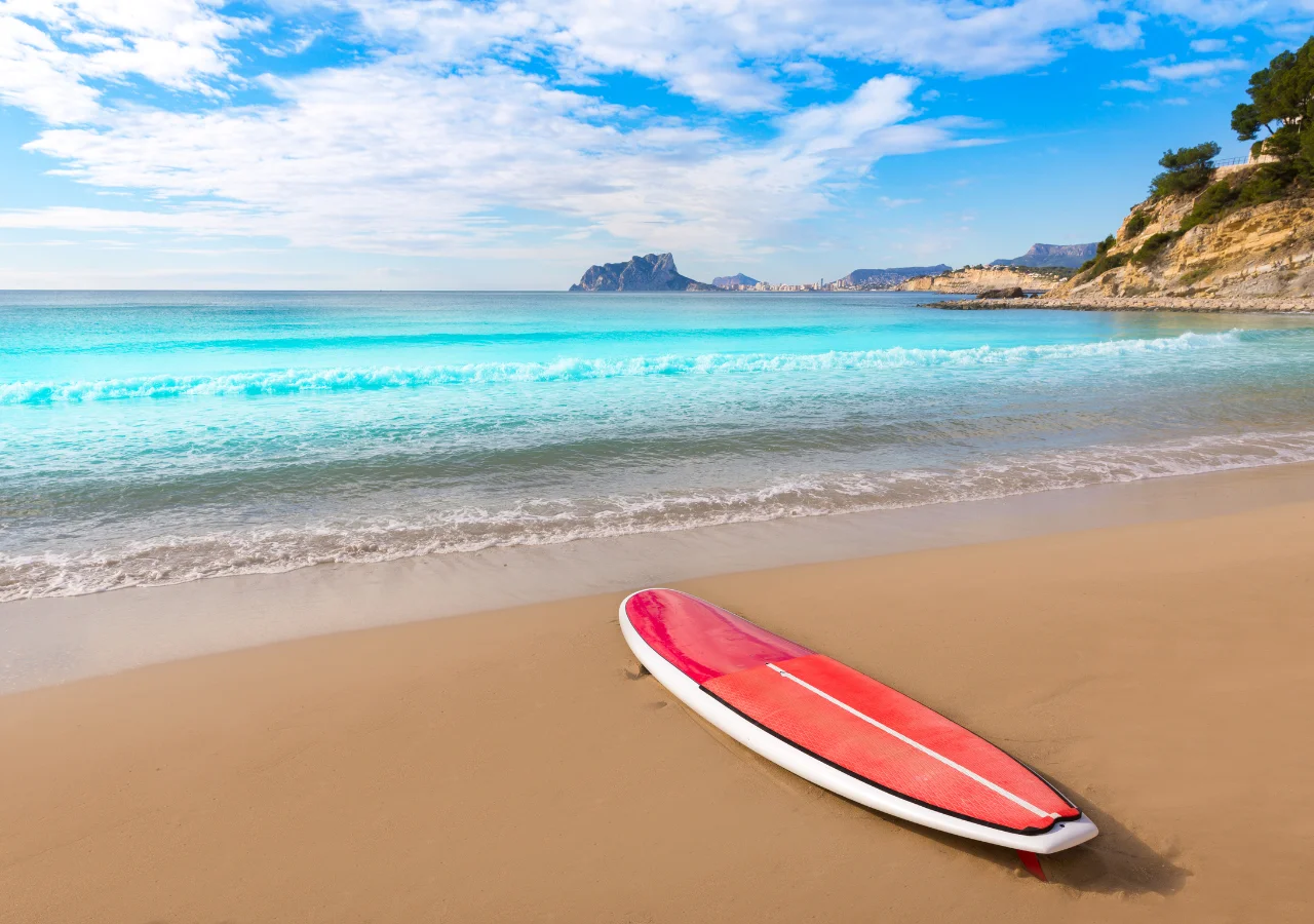 Playa del Portet de Moraira con una tabla de surf